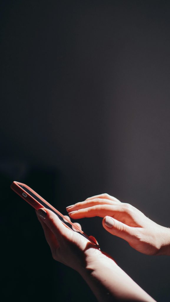 Hands interacting with a smartphone in a well-lit setting, emphasizing connection and technology.